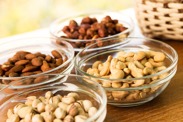 Assortment of mixed nuts and wicker basket on wood table background