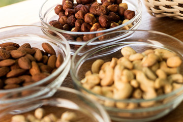 Assortment of mixed nuts and wicker basket on wood table background