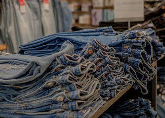 Piles of jeans on a counter in shop. Fashion and shopping concept