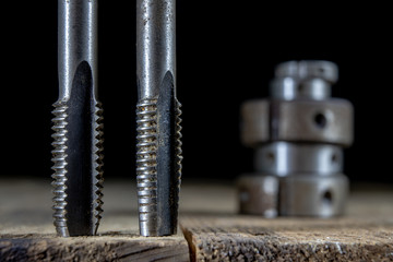 Metalwork tools on the workshop table. Threading dies and taps in an old dusty workshop.