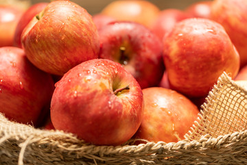 close up of freshly picked apples in a wicker basket with some burlap