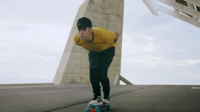 Epic Portrait and close upt of a Young Attractive Trendy Man skateboarding fast under a solar panel on a morning sunny day with an urban city background in slow motion