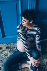 Obraz na płótnie Canvas Pregnant smiling woman sitting on wooden floor in room. . Maternity. Motherhood.