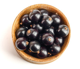 black currant in wooden bowl isolated on white background. Top view. Flat lay pattern