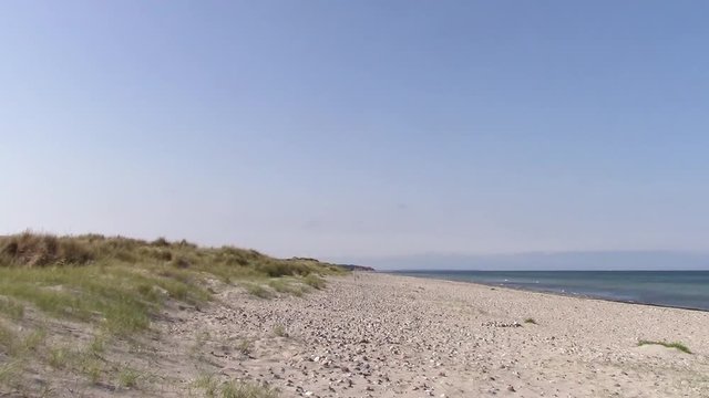 Liseleje Beach by Tisvilde forest and coastal area on the Danish island of Zealand. A pristine spring morning  with a sunny clear blue sky. Beautiful beach stones. Sand dunes with reeds.