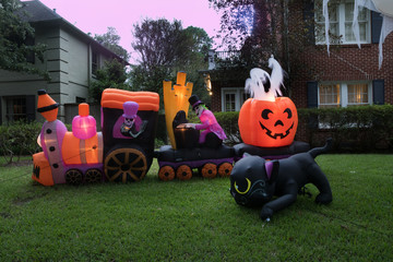 The house is decorated for Halloween: Inflatable train with the dead, big pumpkin, ghost and black...