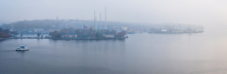 panorama view of boat cruising the harbor in stockholm in morning mist