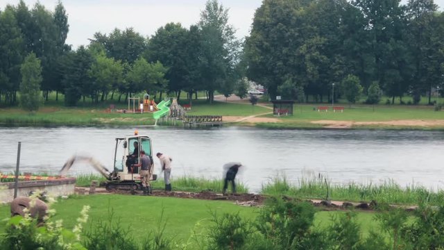 A mini excavator burying the pit on the bank of the river. Time lapse