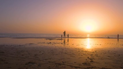 Silhouette of father with two children in the beach at sunset
