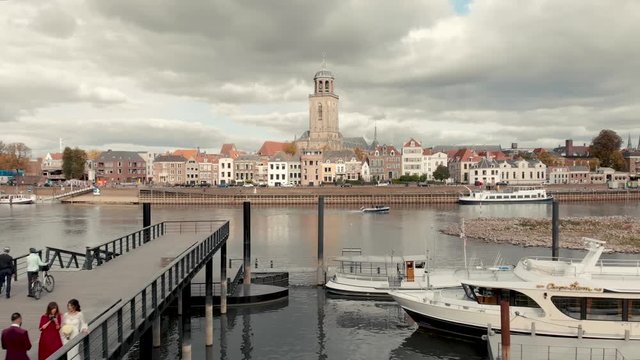 Aerial drone shot of the Dutch medieval city of Deventer starting off showing the pier on the other side of the river IJssel with a boat passing