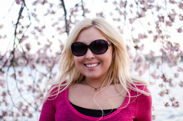 Pretty dusk sunset portrait of a Blonde Woman posing by Cherry Blossom tree in Washington DC during Cherry Blossom Festival