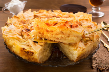A cut piece of cake on a metal spatula, a dough pie with cottage cheese filling and a ruddy baked crust.