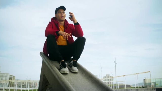 Young Attractive Trendy young Man interacting callling and messaging with a cell phone on an urban city background in slow motion