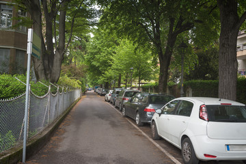 Obraz premium Suburban residential street with modern brick houses and cars parked along the street
