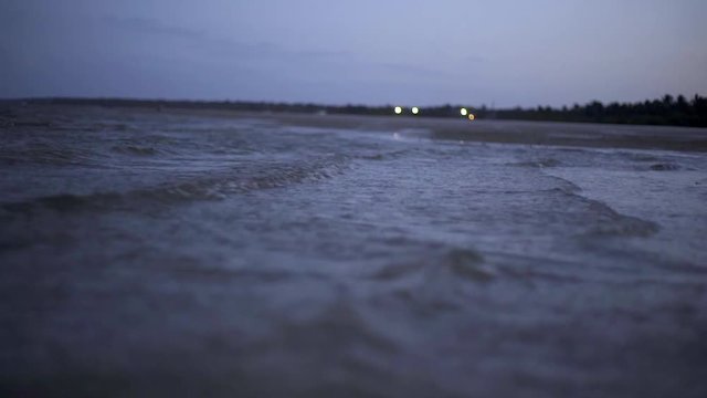 Small Choppy Waves at Ankle Deep Level. Shoreline in Sight, with Lights in the Distance; at Dusk in Vilankulos, Mozambique