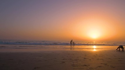 Silhouette of father playing with his son making him flying in the beach at sunset