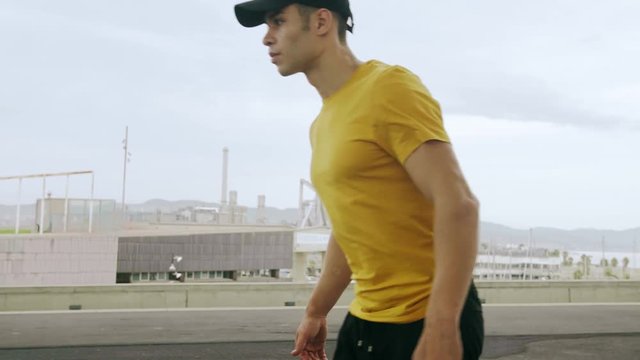 Epic Portrait and close upt of a Young Attractive Trendy Man skateboarding fast under a solar panel on a morning sunny day with an urban city background in slow motion