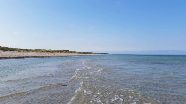 Liseleje Beach by Tisvilde forest and coastal area on the Danish island of Zealand. Early spring morning with a sunny clear sky. Pristine shallow ocean water, gentle waves and beautiful sand ripples.