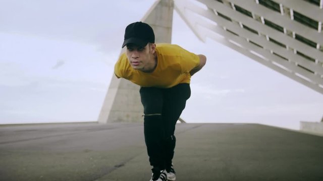 Epic Portrait and close upt of a Young Attractive Trendy Man skateboarding fast under a solar panel on a morning sunny day with an urban city background in slow motion
