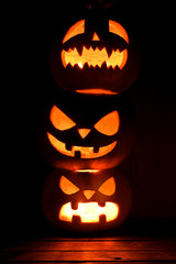 Three Halloween pumpkins on dark background