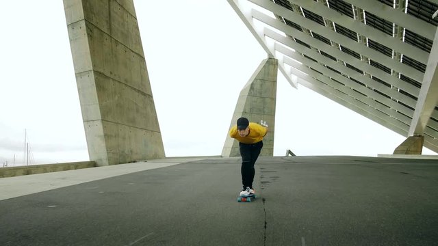 Epic Portrait and close upt of a Young Attractive Trendy Man skateboarding fast under a solar panel on a morning sunny day with an urban city background in slow motion