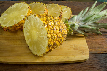 Pineapple on wood texture background. Whole and sliced tropical pineapple on wooden cutting board.