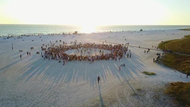 Aerial Drone shot of Crowded Drum Circle at Sunset on Siesta Key, Florida with Beautiful long shadows on the white sand.