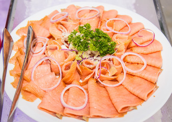 Salmon file served on a plate with fresh vegetable.