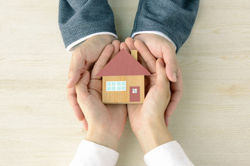 手に包まれた住宅模型