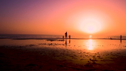 Silhouette of father with two children in the beach at sunset