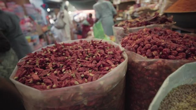 Sun-dried chilies at a grand bazaar market with people passing by