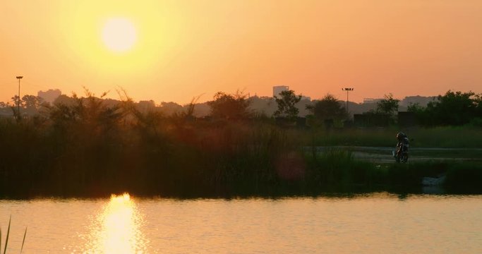 Motorcycle parked next to a lake during sunset