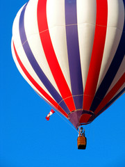 Fototapeta premium Close Up of Red, White And Blue Hot Air Balloon Flying Against Bright Blue Sky
