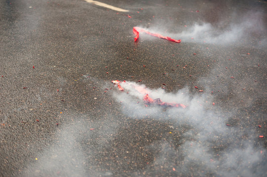 Red firecrackers exploding with smoke on the asphalt for the chinese new year