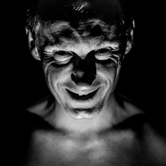 Stylish portrait of adult caucasian man. He smiles like maniac and seems like maniac or crazy. Black and white shot, low-key lighting.