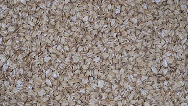 Dry oat flakes grains background, close up rotation loopable 4k top view. Food  background. Gastronomy concept, organic food. Macro rotation oat flakes