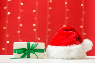 Santa hat with a gift box on a shiny light red background