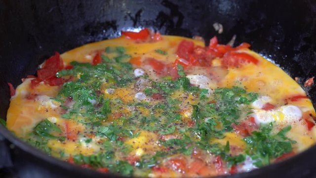 Shakshouka or shakshuka is a North African Jewish origin dish of eggs poached in a sauce of tomatoes, chili peppers and onions, often spiced with cumin. Scrambled eggs with vegetables. Close up