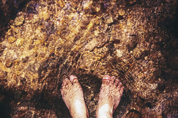 a man soaking barefoot in stream