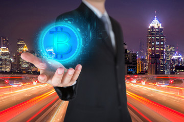 Businessman holding the glowing bitcoin currency digital icon on light trails street, urban in the night as business, innovation, intelligent, investment, stock and income concept.