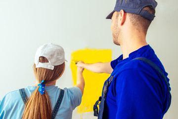 Couple coloring walls together into the yellow with paintbrush