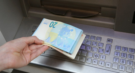 boy takes banknotes euro with hand at ATM
