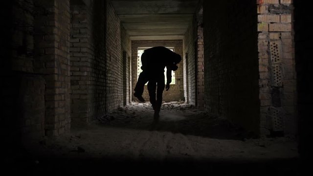 Brave military medic evacuating wounded fellow from battlefield, carrying him on his shoulders in ruined building. Army soldier saving life of wounded and unconscious comrade during combat.