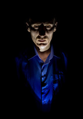 Obraz premium Stylish dark portrait of adult caucasian man who seems like maniac or psycho. Isolated on black background. Low-key lighting.