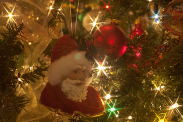 Closeup of part of a lit artificial Christmas tree with Santa ornament