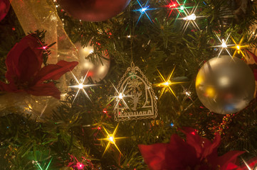 Closeup of part of a lit artificial Christmas tree with a brass Louisiana ornament