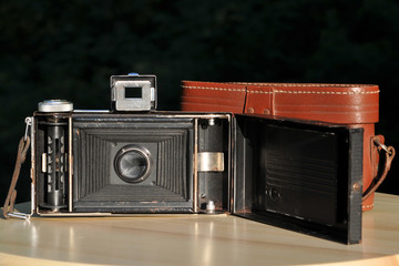 Old folding camera with an open back cover, internal view of the lens, camera bellows and spool for...