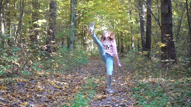 Young flexible girl  is engaged in acrobatics on nature in autumn, outdoors, slow motion. Teenager girl doing acrobatic stunt in forest