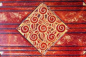 Red and gold solar motif of spirals and petals in a rhombus