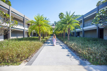 Fototapeta na wymiar Woman walking through the palm trees alley